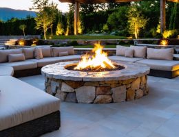Luxurious natural stone fire pit setup with granite, limestone, and fieldstone, featured in a stylish outdoor space with plush seating and ambient lighting under a twilight sky.