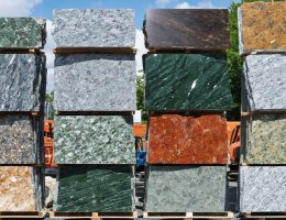 A collection of colorful granite remnants of various sizes, neatly stacked in a stone yard, illustrating affordability and luxury.