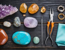 A collection of colorful natural stones and jewelry-making tools, including pliers and wire cutters, displayed on a wooden surface, highlighting the materials and tools used in creating beautiful stone jewelry.