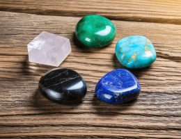 A collection of the five sacred stones – quartz crystal, jade, lapis lazuli, turquoise, and obsidian – elegantly arranged in a circular pattern on a wooden surface, representing their enduring spiritual and cultural significance.