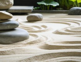 Peaceful Japanese Zen garden featuring smooth stones arranged in meditative formations, surrounded by raked sand patterns and a gentle stone water feature promoting relaxation and mindfulness.