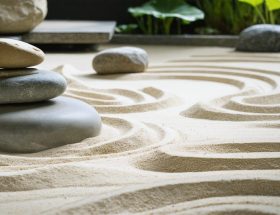 Peaceful Japanese Zen garden featuring smooth stones arranged in meditative formations, surrounded by raked sand patterns and a gentle stone water feature promoting relaxation and mindfulness.