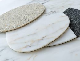 Close-up of a polished quartz countertop with an array of diamond polishing pads ranging from coarse to fine grits, illustrating the transformation process from rough to mirror-like finish.