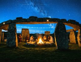Artistic depiction of a megalithic stone circle with celestial alignments and ghostly figures in traditional clothing celebrating, symbolizing the connection between ancient and modern stone festivals.