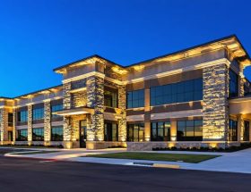 Modern office building exterior featuring stone veneer cladding with architectural nighttime lighting, highlighting the rich texture and contemporary design of the facade.