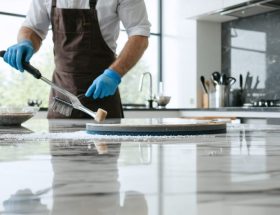 A professional polisher working on a quartz kitchen countertop, demonstrating the transformation from a dull to a mirror-like finish under natural lighting.