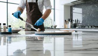 A professional polisher working on a quartz kitchen countertop, demonstrating the transformation from a dull to a mirror-like finish under natural lighting.