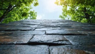 "Stone structure surrounded by green foliage under an overcast sky, illustrating resilience against climate-related challenges."