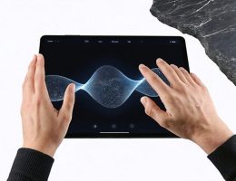 A hand interacting with a digital tablet displaying a realistic stone texture, illustrating haptic feedback technology. The image shows vibrations and waves on the screen, merging the digital and physical realms.