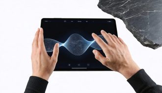A hand interacting with a digital tablet displaying a realistic stone texture, illustrating haptic feedback technology. The image shows vibrations and waves on the screen, merging the digital and physical realms.