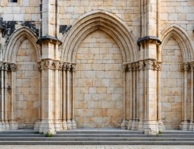 "Close-up of a medieval church's towering stone facade, showcasing intricate masonry and arches in soft natural light."