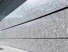 "An elegant granite wall cladding on a modern building facade with a blurred urban skyline in the background."