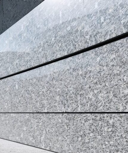 "An elegant granite wall cladding on a modern building facade with a blurred urban skyline in the background."