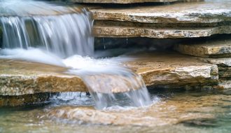 "Clear water cascading over layered granite, slate, and limestone, demonstrating natural filtration."