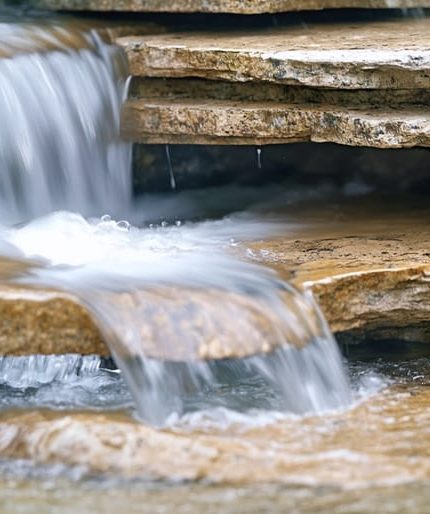 "Clear water cascading over layered granite, slate, and limestone, demonstrating natural filtration."