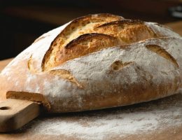 "A professional-grade baking stone with freshly baked artisanal bread, emphasizing the bread's texture and crisp crust in a kitchen setting."