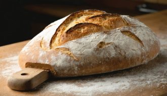 "A professional-grade baking stone with freshly baked artisanal bread, emphasizing the bread's texture and crisp crust in a kitchen setting."