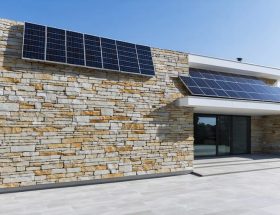 Modern building facade featuring integrated solar panels within granite stone panels, showcasing the blend of traditional architecture with renewable energy technology.