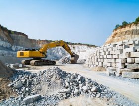"Modern stone quarry with machinery operating in an environmentally conscious manner against a clear blue sky."