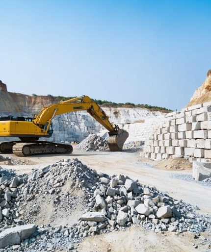 "Modern stone quarry with machinery operating in an environmentally conscious manner against a clear blue sky."