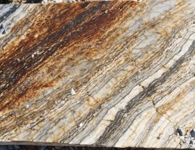 Close-up of a granite surface with rust-colored oxidation streaks, fine pitting, and exposed quartz and feldspar crystals, side-lit by warm sunlight, with a softly blurred outdoor background.