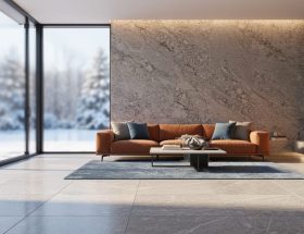 Modern living room with thick limestone floor and granite accent wall illuminated by low winter sunlight through south-facing windows, with a snowy garden softly blurred outside.