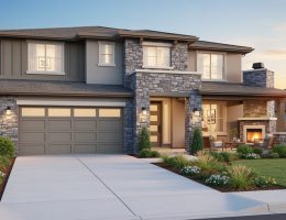Two-story contemporary home with ledgestone accent wall framing the entry and garage, photographed at golden hour with landscaped front yard and a covered patio with stone fireplace in the background.