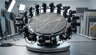 Circular array of DSLR cameras forming a photogrammetry rig around a veined natural stone slab on a motorized turntable in a studio, side-lit to highlight texture, with workshop equipment softly blurred in the background.
