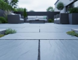 Bluestone pavers on an outdoor patio with visible stone texture and greenery between slabs, photographed in soft natural daylight.