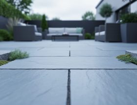 Bluestone pavers on an outdoor patio with visible stone texture and greenery between slabs, photographed in soft natural daylight.